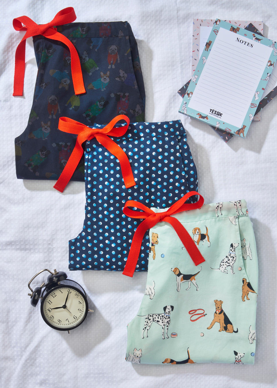 Tessie clothing poppy dog print pyjama trousers with airedale terriers on them, Dalmatians, beagles and westies, rascal print pyjama trousers made with cotton liberty fabric featuring corgis, collies and bulldogs and a dotty print pyjama trousers. all with red drawstring and pockets. matching a5 notepads