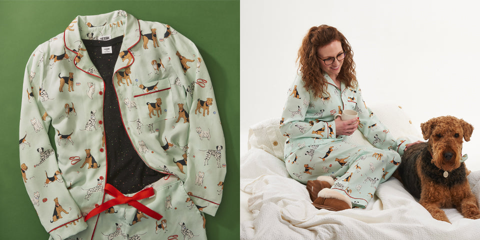 Tessie clothing poppy dog print pyjamas set | model sat on bed with poppy the airedale and model wearing poppy dog print pyjamas featuring airedale terriers, Dalmatians, beagles and westies. aka west highland terriers.