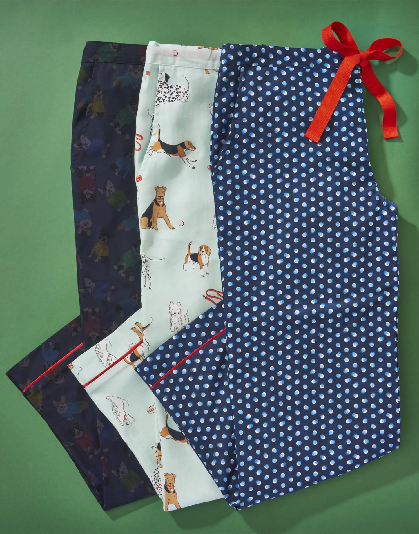 Tessie clothing poppy dog print pyjama trousers with airedale terriers on them, Dalmatians, beagles and westies, rascal print pyjama trousers made with cotton liberty fabric featuring corgis, collies and bulldogs and a dotty print pyjama trousers. all with red drawstring and pockets.